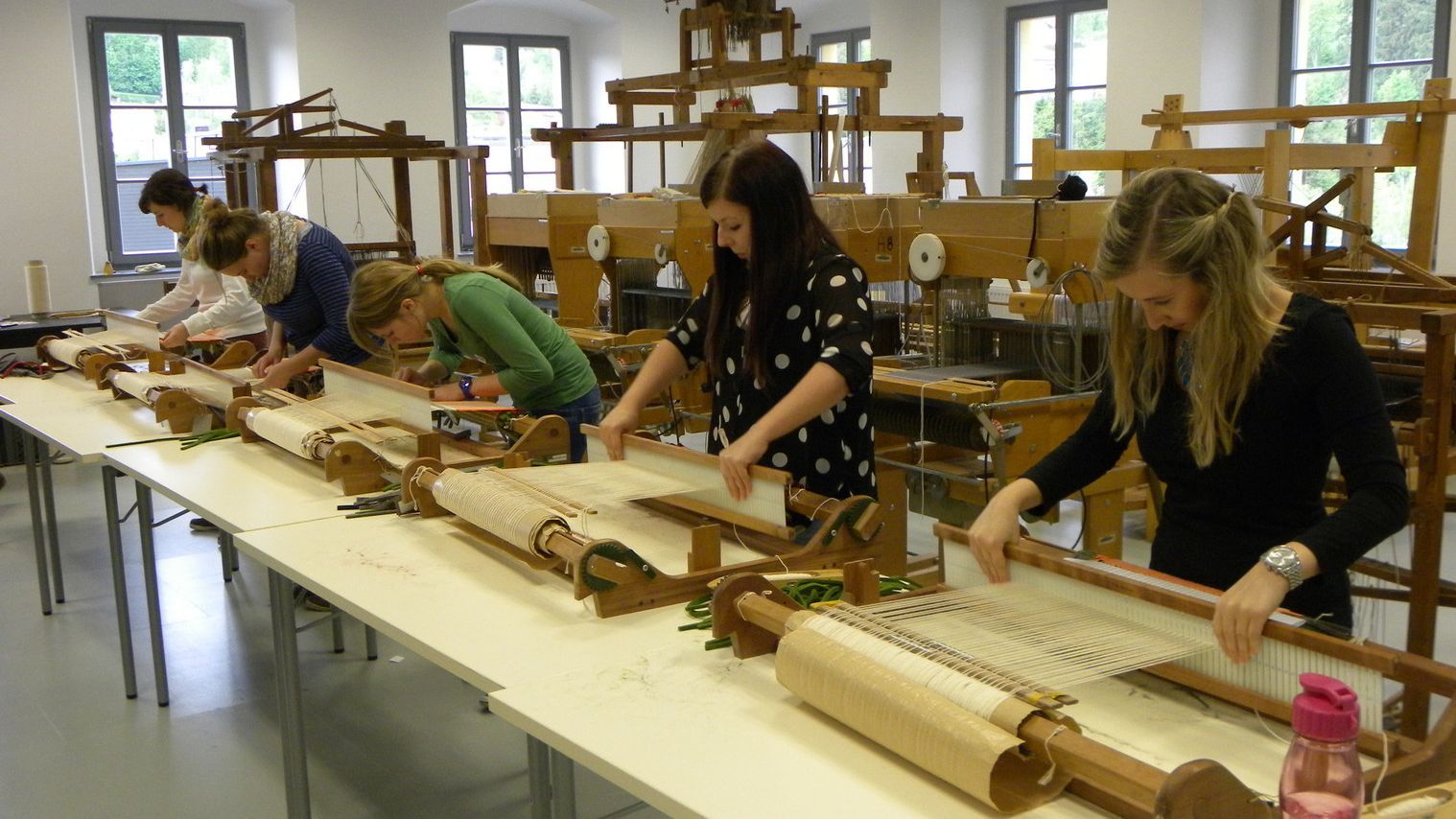 Studierende arbeiten an Tischwebstühlen